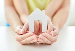 close up of woman and girl hands with paper house